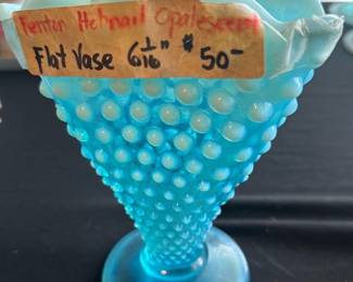 Fenton Blue Hobnail Opalescent Vase — This charming Fenton blue hobnail opalescent vase stands 6 inches tall and features a distinctive hobnail pattern with a flared, ruffled rim. Crafted with opalescent glass, this vintage piece adds a delicate and collectible touch to any room. The vase measures approximately 6 inches in height and has a stable round base. It is in good condition with no visible chips or cracks, though some minor surface wear may be present consistent with age. A classic example of Fenton's artisan glasswork, perfect for collectors or vintage decor enthusiasts.