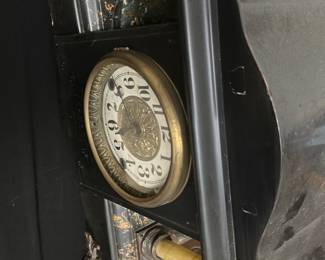 Antique Black Resin Mantel Clock — This antique black mantel clock features elegant brass detailing and ornate columns with a classic design. The clock face displays bold black numerals around a gold embossed center, enclosed in a brass bezel. Measuring approximately 12 inches tall, 16 inches wide, and 6 inches deep, it is a substantial piece ideal for display on a mantel or shelf. The clock shows some wear consistent with age, including minor chipping and surface scratches, but remains a charming vintage collectible. Its Victorian-era styling and craftsmanship make it a distinctive addition for antique enthusiasts.