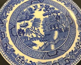 Wedgwood Blue & White — This classic Wedgwood blue and white plate features the traditional Willow pattern design, showcasing intricate scenes of pagodas, bridges, and foliage. Crafted from fine English porcelain, it displays the characteristic blue transfer print on a white background. Measuring approximately 7 inches in diameter, the plate is a lovely example of English decorative china. It shows some fine crazing but remains free from chips or cracks, preserving its vintage charm. Marked on the back with the Wedgwood & Co. England stamp, this plate embodies collectible English pottery craftsmanship.