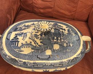 Wedgwood Blue Willow Soup Terrine — This striking Wedgwood soup terrine features the classic Blue Willow pattern, renowned for its intricate blue and white landscape design. Crafted in Etruria, England, this ceramic piece includes a fitted lid with a floral knob and two loop handles for easy serving. Measuring approximately 5.5 inches high, 13 inches wide including handles, and 9 inches deep, it holds ample capacity for elegant table presentation. The terrine is in good condition with some visible age-related wear consistent with vintage Wedgwood pottery. A timeless addition for collectors or those who appreciate fine English china and traditional tableware.