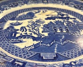 Wedgwood Blue Willow China Plate — This classic Wedgwood Blue Willow china plate features a traditional blue and white pattern depicting a Chinese-inspired landscape. Made in England, this fine china plate is crafted from high-quality porcelain with intricate border designs and central scenic motifs. The plate measures approximately 10.25 inches in diameter, making it an ideal decorative or dining piece. It is in good condition with typical age-related crazing and minor surface wear visible on close inspection. Wedgwood's timeless design and craftsmanship make this plate a valued collectible for both everyday use and display.
