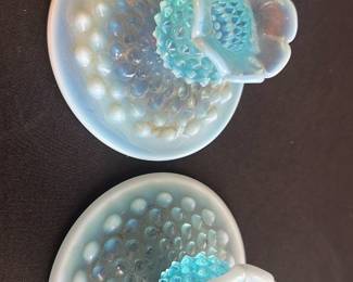 Blue Opalescent Hobnail Candle Holders — These blue opalescent hobnail glass candle holders feature a distinctive hobnail pattern and a flower-shaped candle cup. Crafted of opalescent glass, they reflect light beautifully with a vintage charm perfect for collectors or home display. Each holder measures approximately 3.5 inches in diameter and 2.5 inches in height, making them compact but eye-catching accent pieces. The candle holders are in good condition with slight wear consistent with gentle use over time. Their unique opalescent color and hobnail texture make them a standout vintage collectible for any decor.