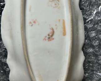 RS Prussia Pink Relish Dish 8-inch — This charming RS Prussia pink relish dish features delicate hand-painted blue swallows against a soft pink and cream background. The porcelain dish measures 8 inches in length and showcases ornate scalloped edges with a pierced handle for easy carrying. It is in good condition with minor signs of age and wear consistent with vintage porcelain. A lovely collector's piece from the RS Prussia line, ideal for display or special serving occasions.