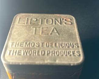 Vintage Lipton's Tea Tin — This vintage Lipton's Tea tin features embossed lettering on the lid that reads 'Lipton's Tea The Most Delicious The World Produces.' The tin is square with a distressed, aged paper label on the sides, indicative of considerable age and use. Measuring approximately 3.5 inches in height and width, this collectible tea tin is a charming piece for any tea enthusiast or vintage tin collector. The condition shows wear with some rust and label deterioration but remains structurally sound with all original parts. A nostalgic collectible from the iconic Lipton brand, ideal for display or storage.