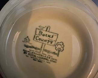 Bucks County Royal Sebring Bowl — This charming Bucks County bowl by Royal Sebring features a detailed countryside design in brown on a cream-colored background. The ceramic bowl depicts a rustic scene with a person drawing water from a well, bordered by floral motifs. It measures approximately 1.75 inches in height and 8.5 inches in diameter, making it a versatile decorative or functional piece. The bowl is in good condition with minor surface wear consistent with vintage use. Produced by Royal Sebring, Ohio, this bowl reflects mid-20th-century American pottery craftsmanship.