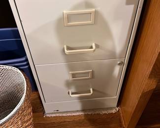 Metal 2-Drawer Filing Cabinet — This white metal 2-drawer filing cabinet offers practical storage ideal for home or office use. Featuring a clean, minimalist design with sturdy handles and label holders on each drawer, it is designed to organize documents efficiently. The cabinet measures approximately 30 inches in height, 18 inches wide, and 20 inches deep, fitting neatly under most desks or countertops. It is in good condition with minor scuffs on the base consistent with regular use. A compact, functional filing solution suitable for a living room office setup.