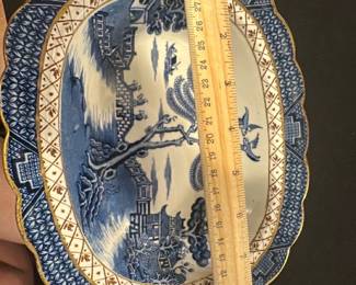 Booths Real Old Willow Blue Platter — This beautiful large platter features the classic 'Real Old Willow' pattern by Booths, made in England. The piece showcases intricate blue willow design with gold accents along the scalloped edge. Measuring approximately 11.5 inches in width, it serves as a charming decorative or serving piece in any collection. The ceramic platter is in good condition with some expected light surface wear and no visible chips or cracks. A timeless example of traditional English transferware, perfect for collectors or vintage kitchen decor.