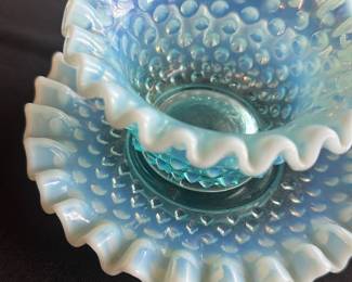 Fenton Blue Opalescent Hobnail Bowl Set — This charming Fenton blue opalescent hobnail bowl set features a delicate ruffled edge and the signature hobnail texture. Crafted in vintage art glass, the bowl nestles into a matching plate, both radiating an iridescent blue color with a milky white opalescent rim. The bowl measures approximately 3.5 inches tall with a 4.5-inch diameter, and the plate is about 6.5 inches wide. Both pieces are in excellent vintage condition without chips or cracks, showcasing Fenton's renowned craftsmanship. A lovely collectible for vintage glassware enthusiasts.