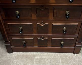 Mahogany 4-Drawer Chest — Solid mahogany four-drawer chest with classic panel fronts and decorative brass-and-black drop pulls. Rich warm wood finish, molded top edge and recessed drawer panels give this piece a traditional look ideal for a master bedroom. Overall footprint is medium—good for dresser or storage in a bedroom or guest room. Good estate condition with light surface wear and scuffs consistent with normal use; drawers appear functional with original hardware.