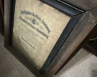 Framed Embalming Diploma — Framed diploma from the New England Institute of Anatomy for Sanitary Science & Embalming, presented in a wide wood frame with inner black rabbet and aged visible paper. The document shows heavy toning, foxing and edge wear consistent with age; frame has surface wear and small chips but remains solid for display. Overall dimensions estimated to fit a standard large diploma frame; good display piece for medical or mortuary collectors and period decor. Sold as-is due to paper age, staining, and frame blemishes; frame can be refinished and document conserved if desired.