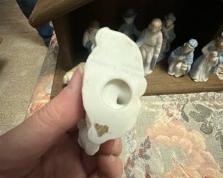 Porcelain Nativity Figurine Set — Charming porcelain nativity figurine set displayed in a simple wooden stable; figures feature soft blue and cream glazes and include Mary, Joseph, baby Jesus in manger, three wise men, shepherd and animals. The figures are small, delicately molded porcelain with glossy finish and hand-painted blue accents; stable is unfinished wood. Overall compact tabletop set good for holiday mantle or table display; figures are lightweight and easy to arrange. Condition is good overall with typical minor edge wear and a small chip on one figure base as shown.
