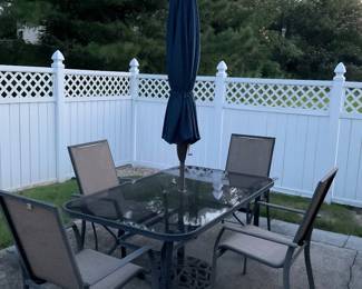 Glass top patio table with four chairs, sun umbrella and heavy umbrella stand