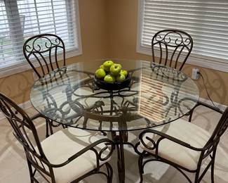 Kitchen table - glass top with decorative metal base. Four matching chairs with cushioned seats