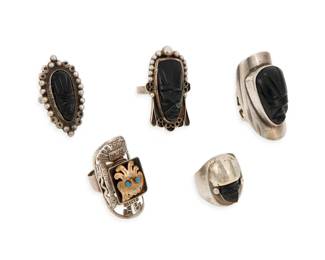 289 Five Mexican silver and hardstone rings Mid/late 20th century Two marked for Mexico; three marked for sterling A group comprising four silver rings with carved set black stone mask motifs and one stamped silver openwork ring with central diminutive gold tone mask motif with blue stone eyes 5 pieces Ring sizes: 7 (+, expandable) to 5.25 52.5 grams gross Estimate: $200 - $400