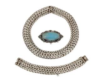281 Three Mexican silver jewelry items Mid-20th century Each stamped: Silver / Mexico Comprising a chunky silver herringbone link choker necklace, together with a matching silver link bracelet, as well as a sculptural sterling silver oval brooch with a set blue stone cabochon and silver overlay curls 3 pieces Necklace:12.5" inner C x 0.75" H; Bracelet: 7" L x 0.75" H; Brooch: 1.25" H x 2.5" W 246.6 grams gross Estimate: $300 - $500