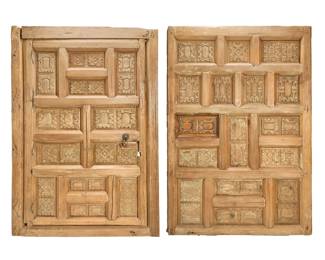 128 A pair of Mexican carved wood doors 19th century Each with recessed carved decorative panels, one mounted with a wrought-iron floral medallion pull 2 pieces Larger: 86.5" H x 61" W x 4" D; Smaller: 85.5" H x 60" W x 5" D Estimate: $1,200 - $1,800