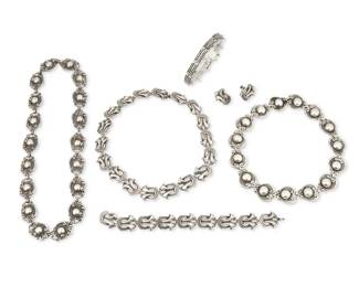 276 Margot Van Voorhies (aka Margot de Taxco, ca. 1896-1985, American) A group of Mexican silver jewelry Circa 1948-1978; Taxco, Mexico Each stamped: Margot de Taxco / Sterling / Made in Mexico / [Eagle 16] / [Design number] Six works in sterling silver comprising a "Furls and Circle" openwork scroll link necklace (No. 5306; 15.5" L x 0.75" H), with a matching link bracelet (7.5" L x 0.75" H) and a pair of earclips (Each: 0.75" H), as well as a long link necklace with elaborate scroll and ball links (No. 5270; 19.5" L x 0.75" H), a smaller scroll and ball link necklace (No. 5210; 14.75" L x 0.75" H), and a narrow dotted link bracelet with charm loops (No. 5672; 7.375" L x 0.5" H) 7 pieces 264.7 grams Estimate: $800 - $1,200