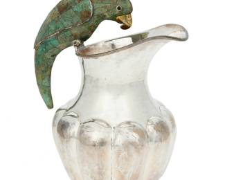 269 A Los Castillo silver-plated figural pitcher Circa 1939-1962; Taxco, Mexico Impressed to underside: R / LOS CASTILLO TAXCO / TA-01 / PLATEADO Mounted with a green hardstone overlay parrot handle above a lobed body 10" H x 8" W x 5.875" D Estimate: $800 - $1,200
