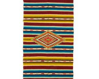 45 A Mexican Rainbow Saltillo sarape Circa 1930s Finely woven in green, blue, brown and cream wool and silk with an elaborate central serrated concentric diamond with silver metal thread accents, multiple ombre shaded bands and contrast banded motifs, with knotted fringing to each end 80" H x 35.5" W approximately Estimate: $300 - $500