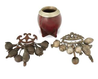 164 Three South American objects 19th/20th century One amulet impressed indistinctly Comprising two Afro-Brazilian Penca de Balangandan metal alloy amulets, and a leather-clad gourd and metal yerba maté vessel 3 pieces Maté: 4.25" H x 3.875" Dia.; Larger amulet: 6.25" H x 5" W x 3" D Estimate: $150 - $250