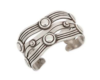 272 William Spratling (1900-1967, American) A 'River of Life' sterling silver cuff bracelet Circa 1940-1946, First Design Period; Taxco, Mexico Stamped for William Spratling; further stamped: Made in Mexico / Silver Designed as incised silver waves with applied narrow Aztec rings 6.625" total inner C x 1.375" H, gap: 1" 88.4 grams Estimate: $800 - $1,200