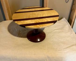 Handcrafted hardwood pedestal cake stand with contrasting wood stripes. Ideal for displaying cakes, desserts, candles, or decorative centerpieces.