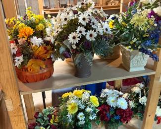 Large assortment of handcrafted floral arrangements featuring daisies, hydrangeas, wildflowers, fall décor, spring florals, and decorative containers ready to display.