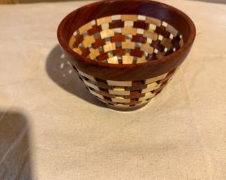 Handcrafted segmented hardwood basket featuring alternating exotic wood species and open lattice construction. Fine artisan woodworking.