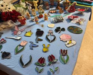 Crafting supplies including stained glass ornaments, handmade suncatchers, figurines, seasonal décor, ribbon, gift bags, floral picks, and assorted craft materials.
