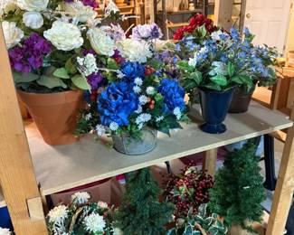 Designer silk floral arrangements in decorative pottery, ceramic, metal, and glass containers including blue hydrangeas, roses, daisies, and seasonal home décor.