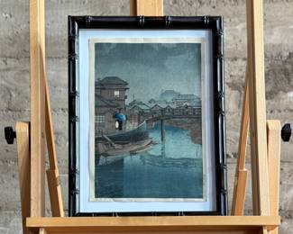 “Rainy Season at Ryoshimachi, Shinagawa”, an original Japanese woodblock print by listed artist, Kawase Hasui. Hand signed circa 1931 and professionally framed. This piece measures (without frame), 15” H x 10.25” W. Kawase Hasui (1883–1957) was the foremost landscape artist of the shin-hanga (“new prints”) movement. Renowned for his serene, atmospheric scenes of snow, rain, and moonlight, he designed approximately 620 woodblock prints over his 40-year career. In 1956, the Japanese government honored him as a Living National Treasure. $2,000 reserve.