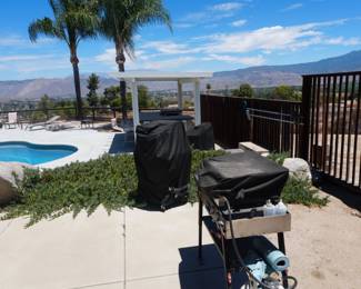 Two outdoor grills with fitted covers/protectors.
