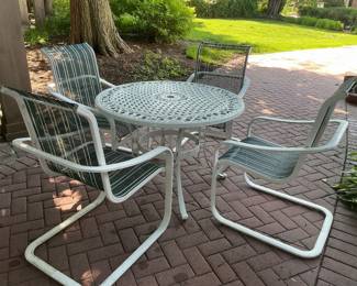 Outdoor iron table with four rocker style chairs.
