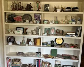 Full shelves of books, bookends, cups and saucers, plates etc