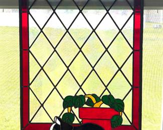 Stained glass suncatcher with  a black and white cat resting near a flower pot.