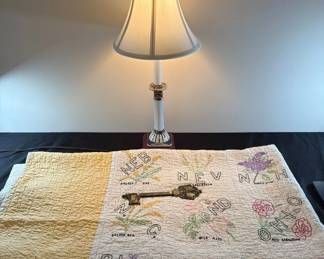 Yellow And White Quilt With States, Table Lamp, And Metal Key