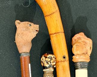 Large collection of walking sticks with human and animal toppers