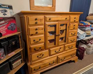 Basset Furniture country knotty pine gentleman's chest features a massive 17 drqwers, inset center glass front doors, and a champagne finish.
