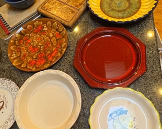 Assorted Ceramic Serving Dishes including Sunflower Bowl, Red Octagonal Platter, Textured Oval Dish, Pie Dish, Lemon Plate by Kier, and Floral Plate