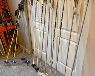 collection of vintage ski equipment, including several pairs of aluminum and fiberglass poles with various basket styles