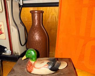 Carved wood duck decoy and pottery bottle