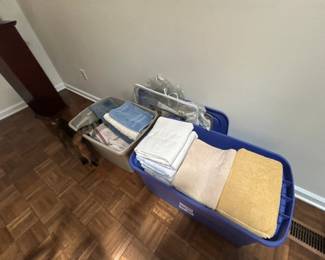 Assorted Towels and Linens in Storage Bins - A collection of assorted towels and linens neatly stored in plastic bins. Ideal for home use or guest accommodations.
