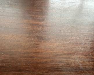 Wooden Table Surface - A smooth wooden table surface with a rich finish, showing minor wear.