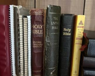 Collection of Bibles and Religious Books - A collection of various Bibles including the Revised Standard Version, The Living Bible, and the New King James Bible, along with other religious texts.