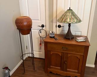 pottery in stand, stained glass lamp, small cabinet