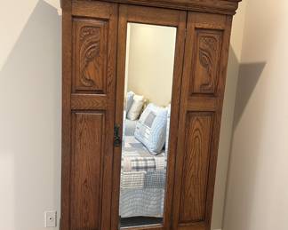 Antique oak armoire with mirrored door, carved panels, single drawer