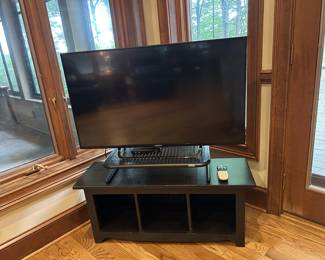 Sony flat-screen TV with black wood TV stand and riser
