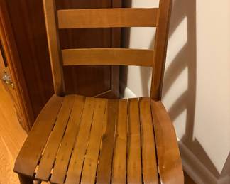 ladder-back children's rocking chair features a natural wood finish and a slat seat