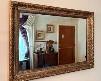ornate antique mirror features a rustic gold finish on its detailed frame and includes bevelled glass