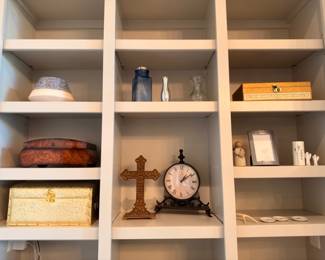 Shelf of home decor, wood cross, clock, and boxes
